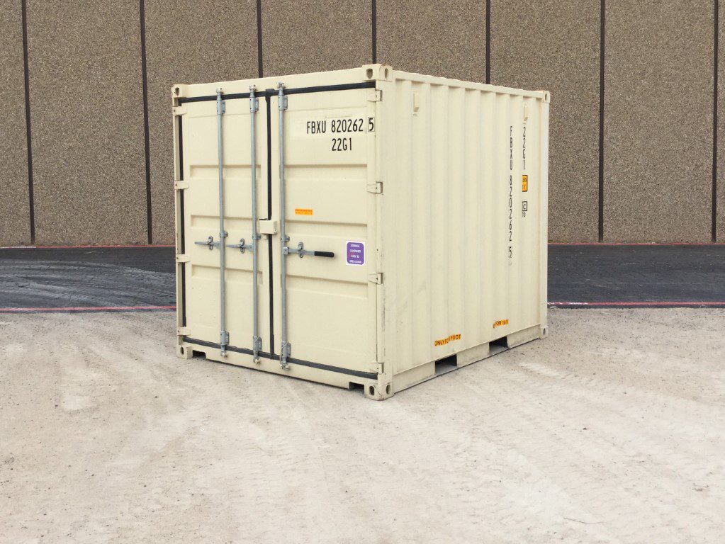 Small beige shipping container on gravel surface.