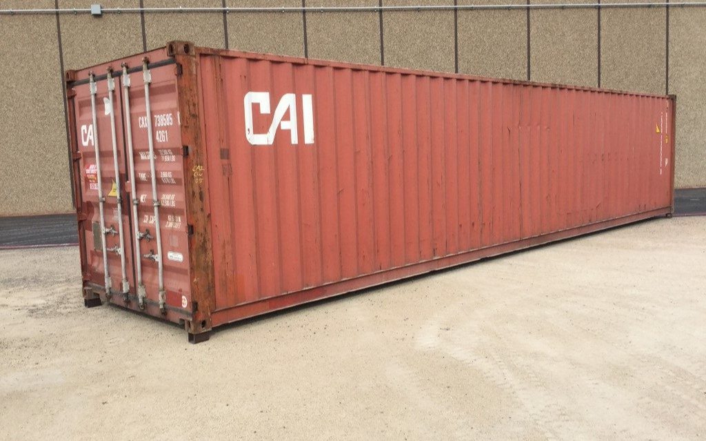 Red shipping container on concrete ground.