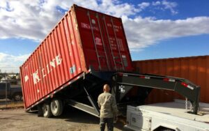 Red shipping container tilted on trailer.