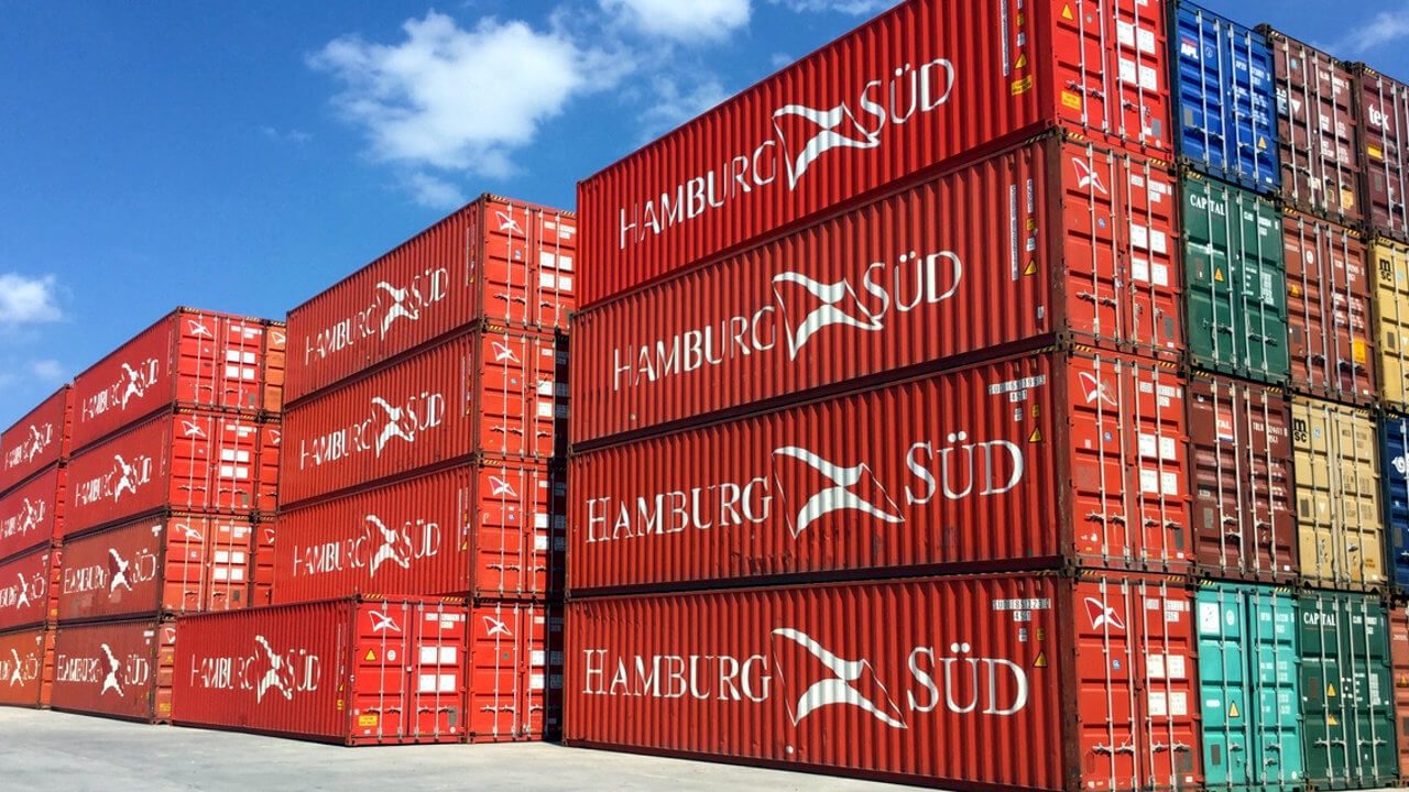 Red shipping containers stacked under blue sky.